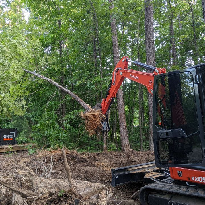 A red and black tractor is in the woods